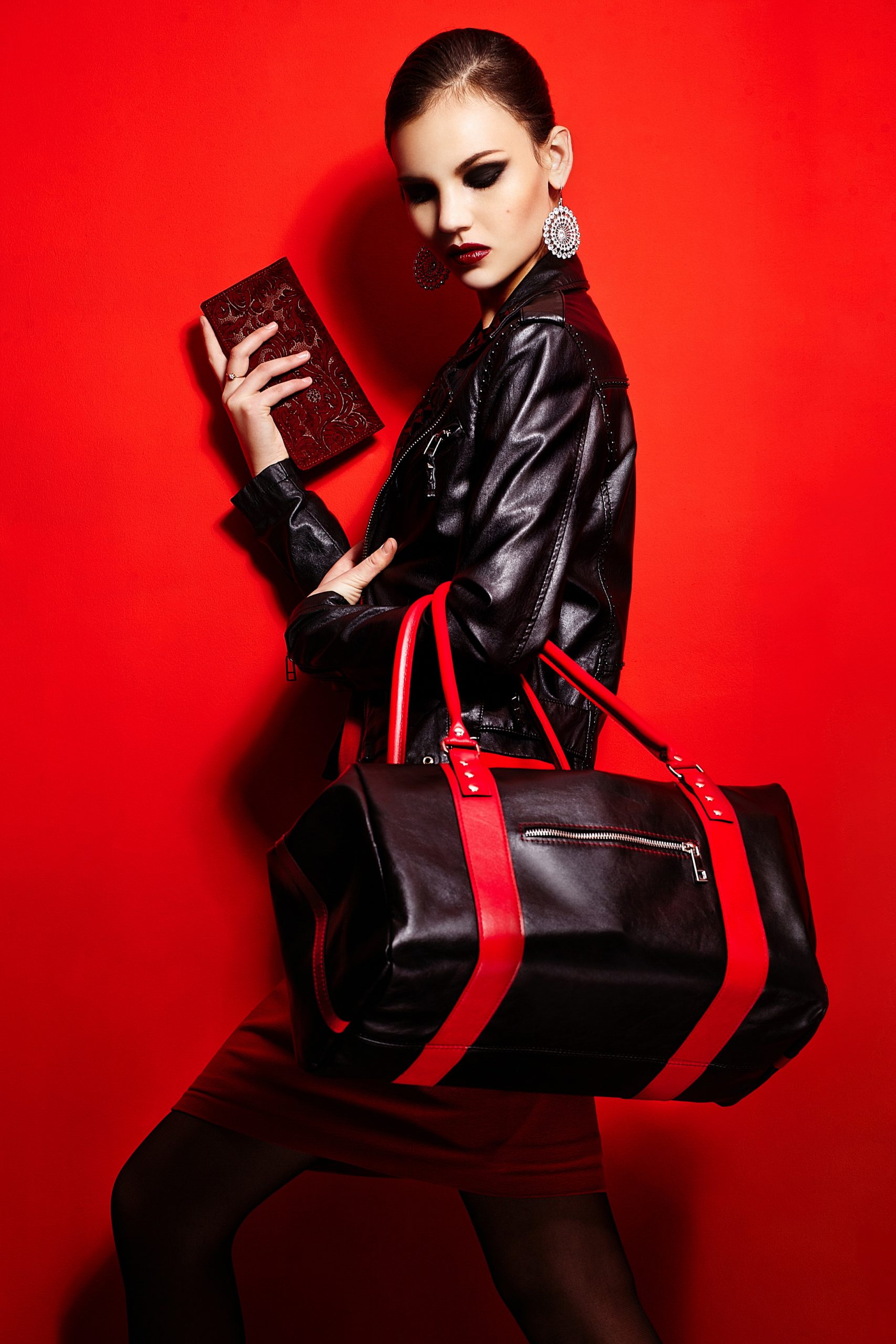 high fashion look.glamor closeup portrait of beautiful sexy stylish brunette caucasian young woman model in black jacket with bag bright makeup, with red lips, with perfect clean skin in studio